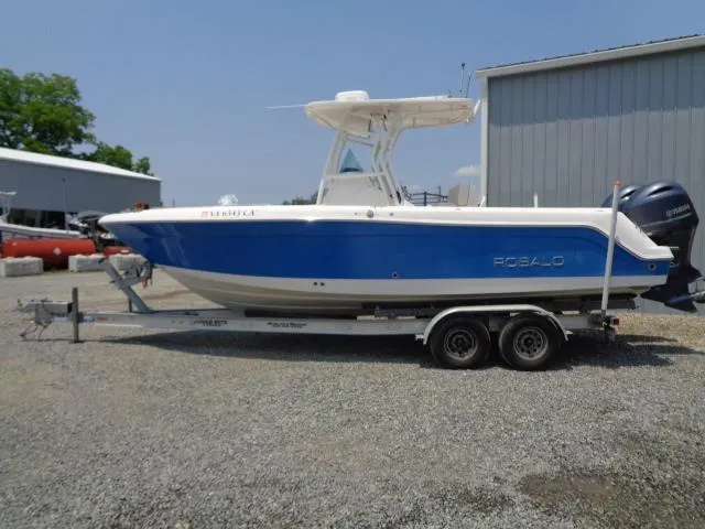 Slide: The Image of 2017 Robalo R260 Center Console boat on trailer, blue and white design, parked outdoors. - 23