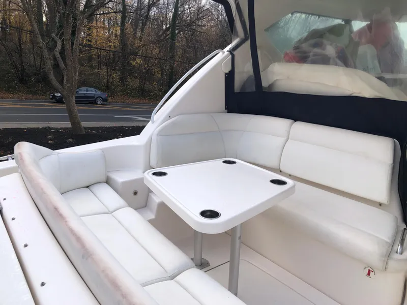Slide: The Image of 2008 Tiara Yachts 3900 Sovran interior with white seating and table, near a wooded road. - 6