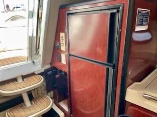 Slide: The Image of 2001 Wellcraft Martinique 3700 interior with wooden cabinetry and compact refrigerator. - 29