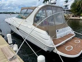 Slide: The Image of 2001 Wellcraft Martinique 3700 boat docked by the water, featuring sleek design and tan canopy. - 6
