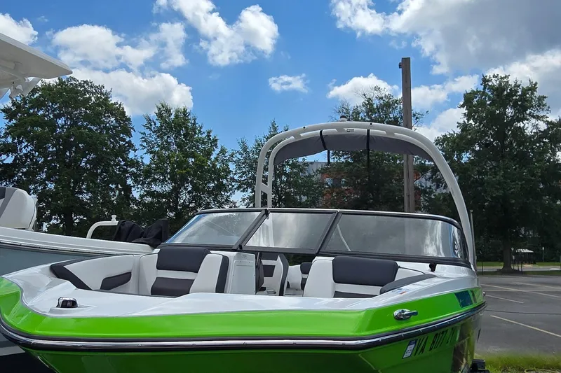 Slide: The Image of 2022 Yamaha AR195 boat with green accents, parked outdoors under a blue sky. - 2