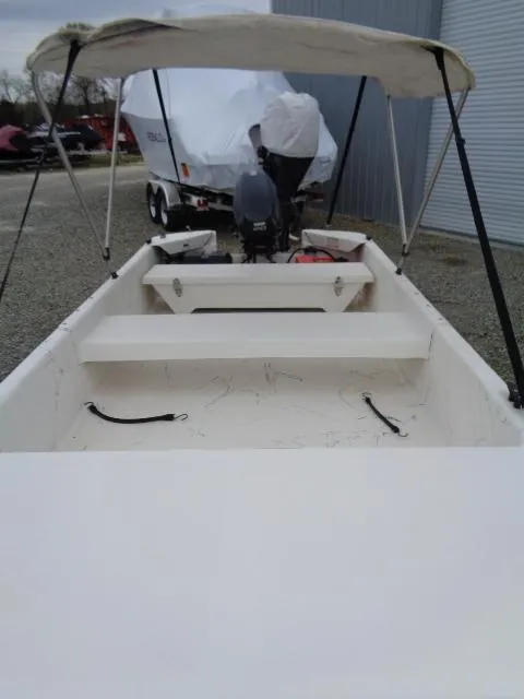 Slide: The Image of Small Sundance K14T boat with canopy, 2010 model, parked on gravel near a covered trailer. - 9