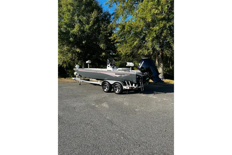 Slide: The Image of 2025 Ranger RB210 boat on trailer, parked outdoors with trees in background. - 2