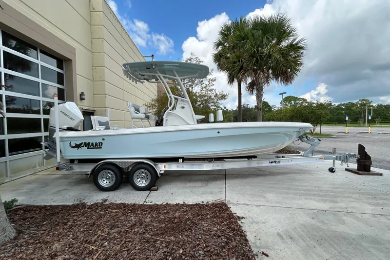 The Image of 2025 Mako 24 APEX boat on trailer, parked near building and palm tree. - 0