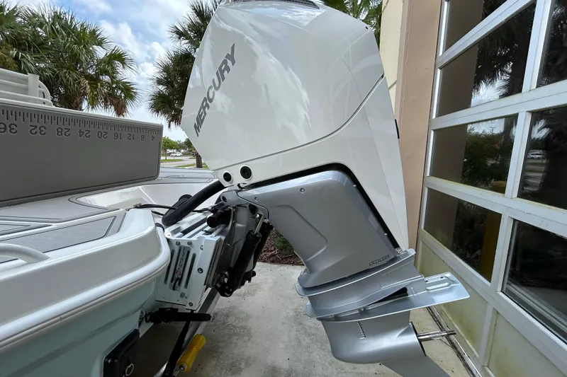 Slide: The Image of 2025 Mako 24 APEX boat with Mercury outboard motor, parked near palm trees. - 4
