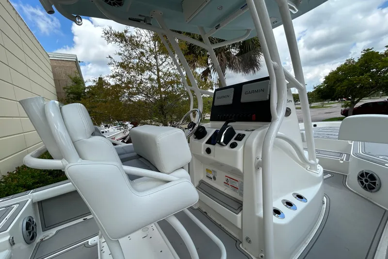 Slide: The Image of 2025 Mako 24 APEX boat interior with dual Garmin displays and white seating. - 6