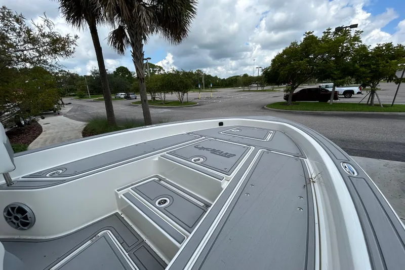 Slide: The Image of 2025 Mako 24 APEX boat deck in a parking lot, surrounded by trees and cloudy sky. - 7