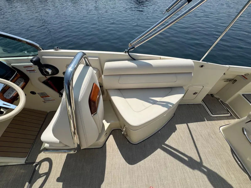 Slide: The Image of 2022 Chris-Craft Launch 28 GT interior with beige seating and steering wheel, docked on water. - 17