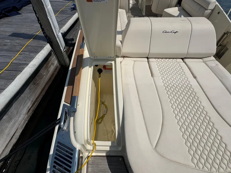 Slide: The Image of 2022 Chris-Craft Launch 28 GT boat interior with open storage compartment and cushioned seating. - 7