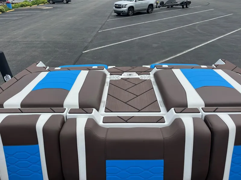 Slide: The Image of 2025 Malibu Wakesetter 23 LSV boat interior with blue and brown seating in a parking lot. - 12