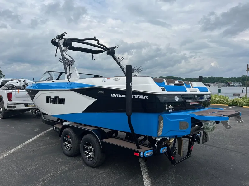 Slide: The Image of 2025 Malibu Wakesetter 23 LSV boat on trailer, parked near a lake. - 3