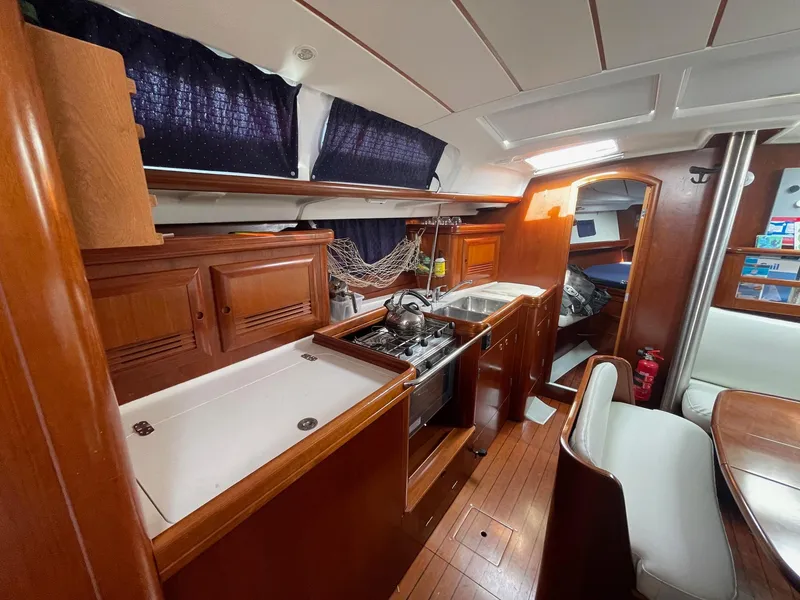 Slide: The Image of Interior of 2003 Beneteau 423 sailboat with wooden cabinetry and compact kitchen area. - 12