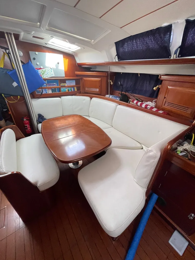 Slide: The Image of Interior of 2003 Beneteau 423 sailboat with white seating and wooden table. - 9