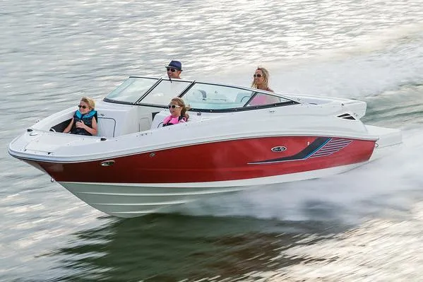 The Image of 2016 Sea Ray 220 Sundeck boat on trailer, parked outdoors under clear blue sky. - 0