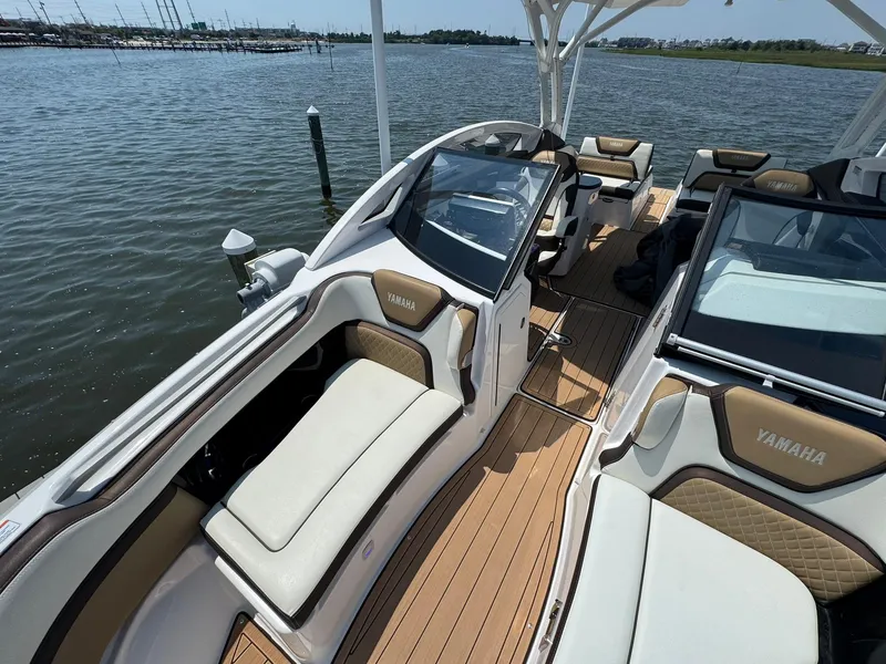 Slide: The Image of 2022 Yamaha Boats 275SD interior with luxurious seating on a calm water backdrop. - 10
