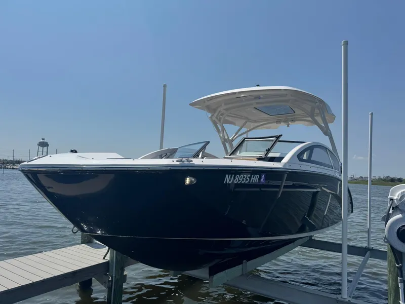 Slide: The Image of 2022 Yamaha Boats 275SD on lift, docked by water, clear sky background. - 17