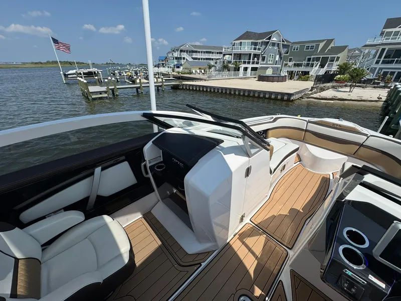 Slide: The Image of 2022 Yamaha Boats 275SD interior with sleek design, docked near waterfront homes. - 4