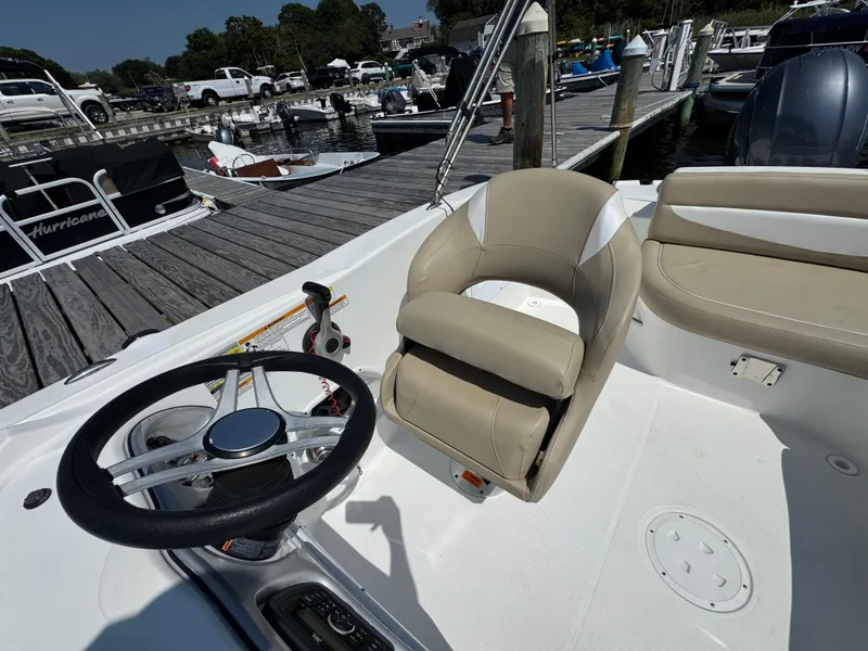 Slide: The Image of 2017 Hurricane SunDeck Sport 203 OB boat interior with steering wheel and seating at a marina. - 14
