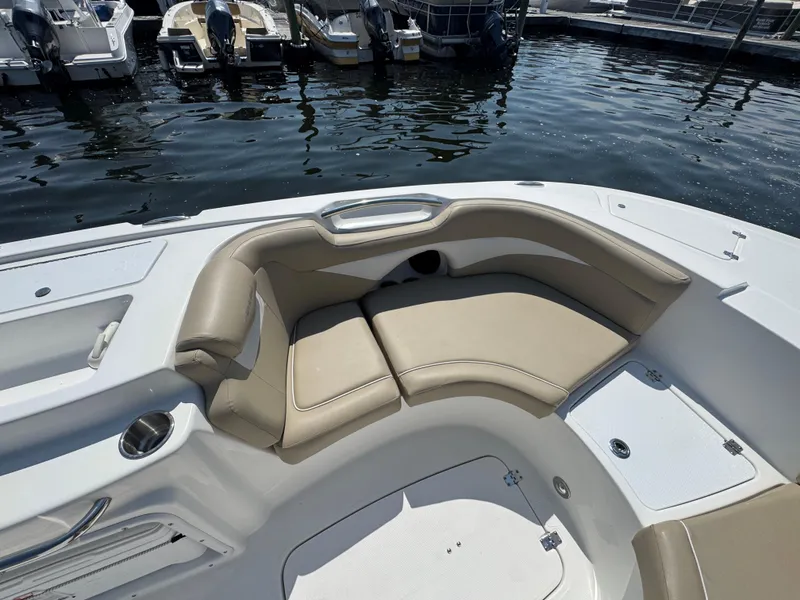 Slide: The Image of 2017 Hurricane SunDeck Sport 203 OB boat interior with beige seating at a marina. - 19