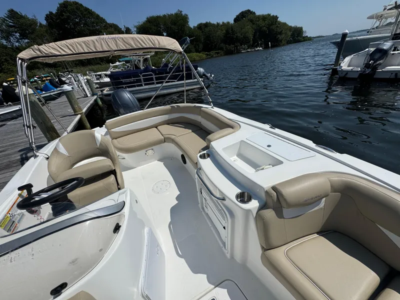 Slide: The Image of 2017 Hurricane SunDeck Sport 203 OB boat interior with seating, docked by a scenic waterfront. - 21