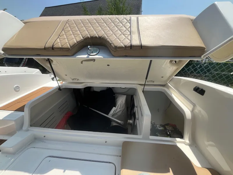 Slide: The Image of 2023 Bayliner DX 2000 boat storage compartment with open cushioned lid. - 12