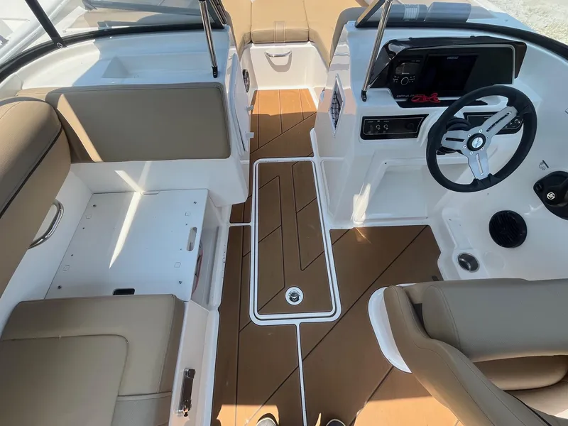 Slide: The Image of 2023 Bayliner DX 2000 boat interior with tan seating and modern dashboard. - 13