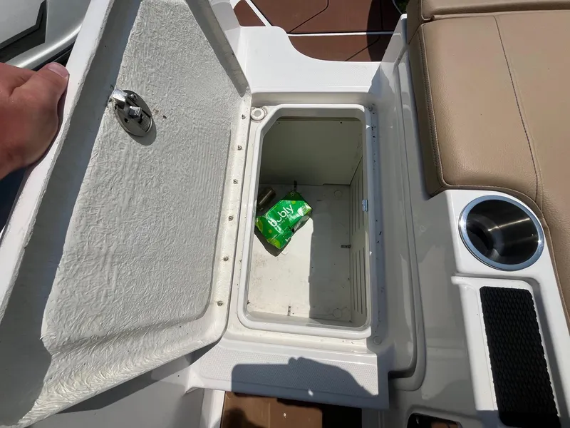 Slide: The Image of Open storage compartment on 2023 Bayliner DX 2000 boat with a drink can inside. - 6