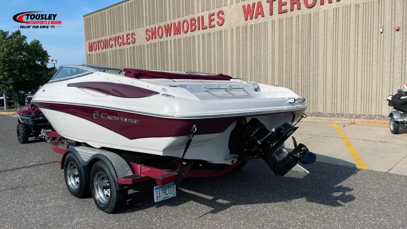 Slide: The Image of 2011 Crownline 21SS boat on trailer outside dealership, showcasing sleek design and dual-tone color. - 2