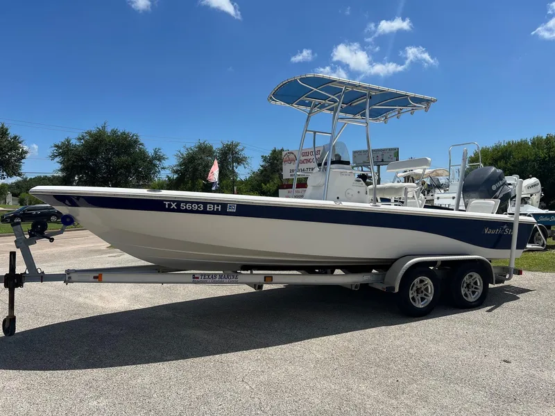 The Image of 2011 NauticStar 2200 Tournament boat on trailer, parked outdoors under blue sky. - 1