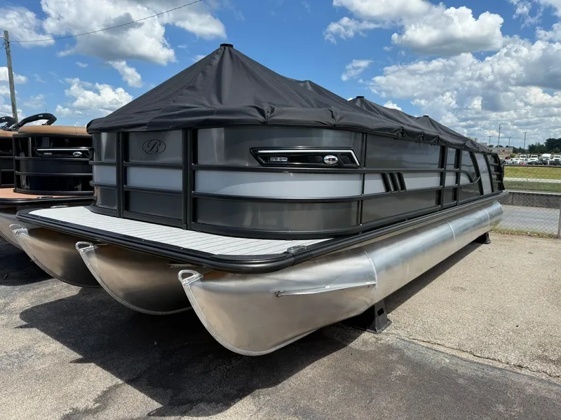 Slide: The Image of 2026 Bentley Pontoons Elite 253 Swingback with cover, parked outdoors under a blue sky. - 3
