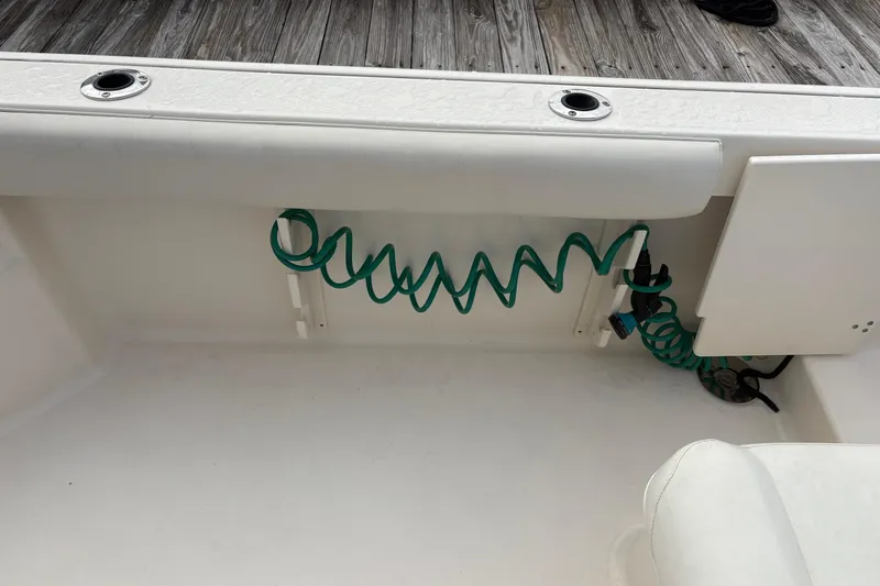 Slide: The Image of 2007 Pursuit OS 285 Offshore boat deck with coiled green hose and storage compartment. - 11
