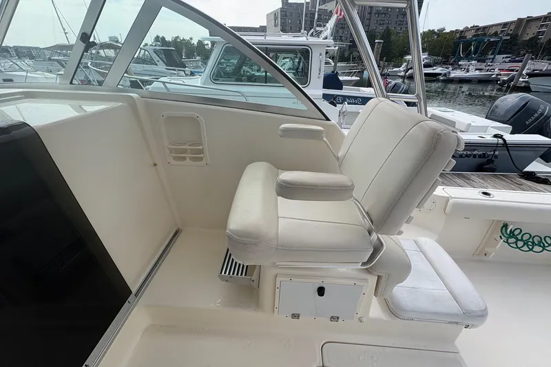 Slide: The Image of 2007 Pursuit OS 285 Offshore boat interior with white seating at a marina. - 12