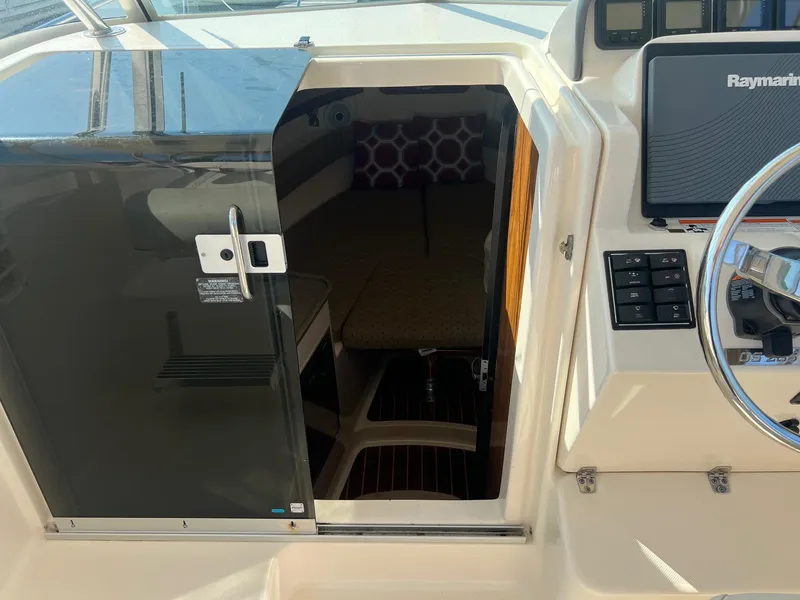 Slide: The Image of 2007 Pursuit OS 285 Offshore cabin entrance with steering console and Raymarine display. - 13