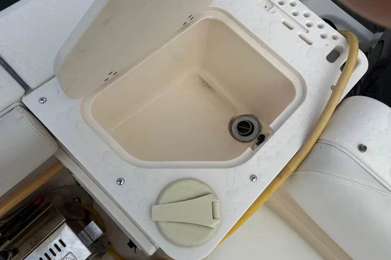 Slide: The Image of 2007 Pursuit OS 285 Offshore boat sink with yellow hose and storage compartment. - 19