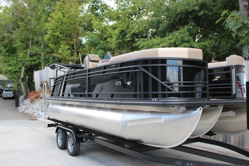 The Image of 2026 Starcraft EXS 1 Q DH pontoon boat on trailer, surrounded by trees. - 3