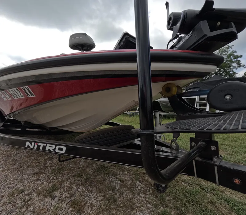 Slide: The Image of 2016 Nitro Z20 boat on trailer, red and white hull, parked on gravel. - 12