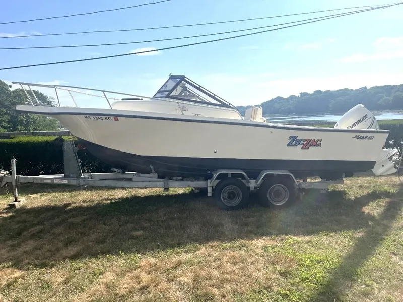 The Image of 1989 Mako 210 WA boat on trailer, parked on grass near water. - 0
