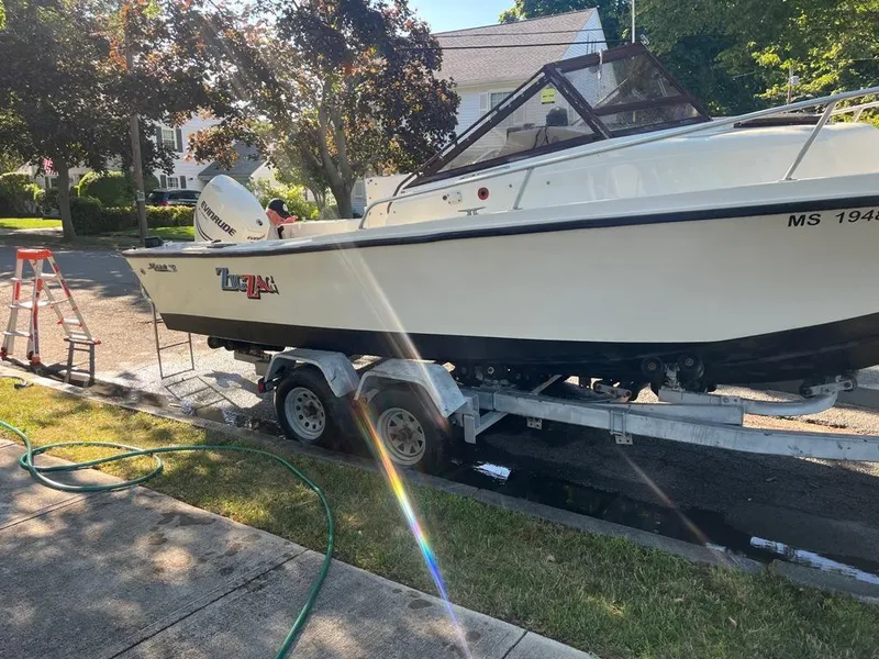 Slide: The Image of 1989 Mako 210 WA boat on trailer, parked on residential street, with ladder and garden hose nearby. - 12
