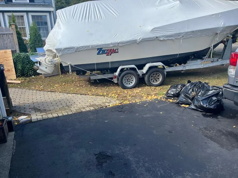 Slide: The Image of 1989 Mako 210 WA boat covered on trailer in driveway. - 16