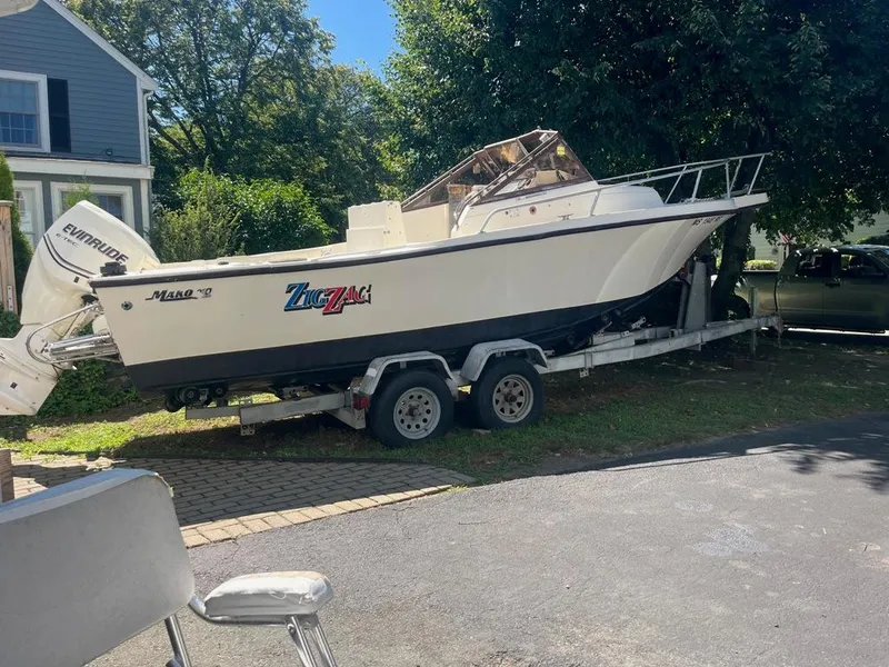 Slide: The Image of 1989 Mako 210 WA boat on trailer, parked outdoors near a house. - 2