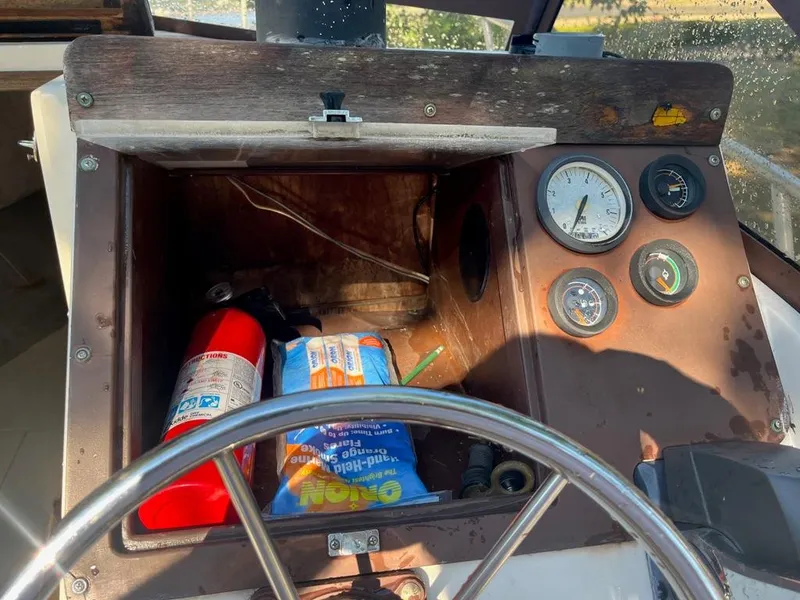 Slide: The Image of 1989 Mako 210 WA boat dashboard with gauges, fire extinguisher, and storage compartment. - 21