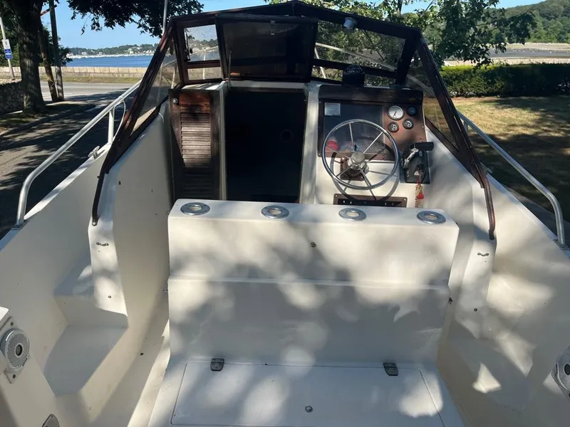Slide: The Image of 1989 Mako 210 WA boat interior with steering wheel, docked near a scenic waterfront. - 24