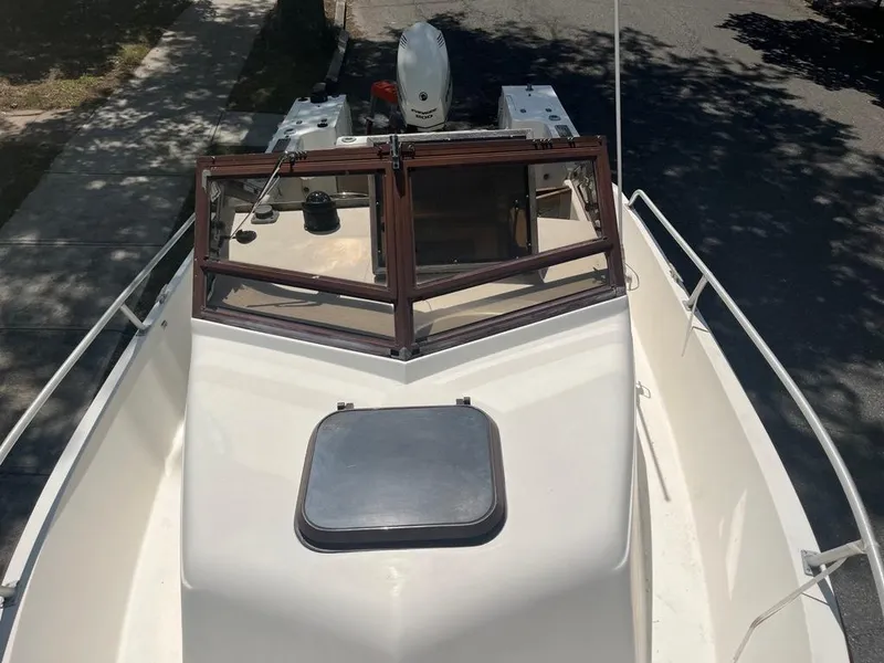 Slide: The Image of 1989 Mako 210 WA boat with windshield and hatch, parked on a street. - 27