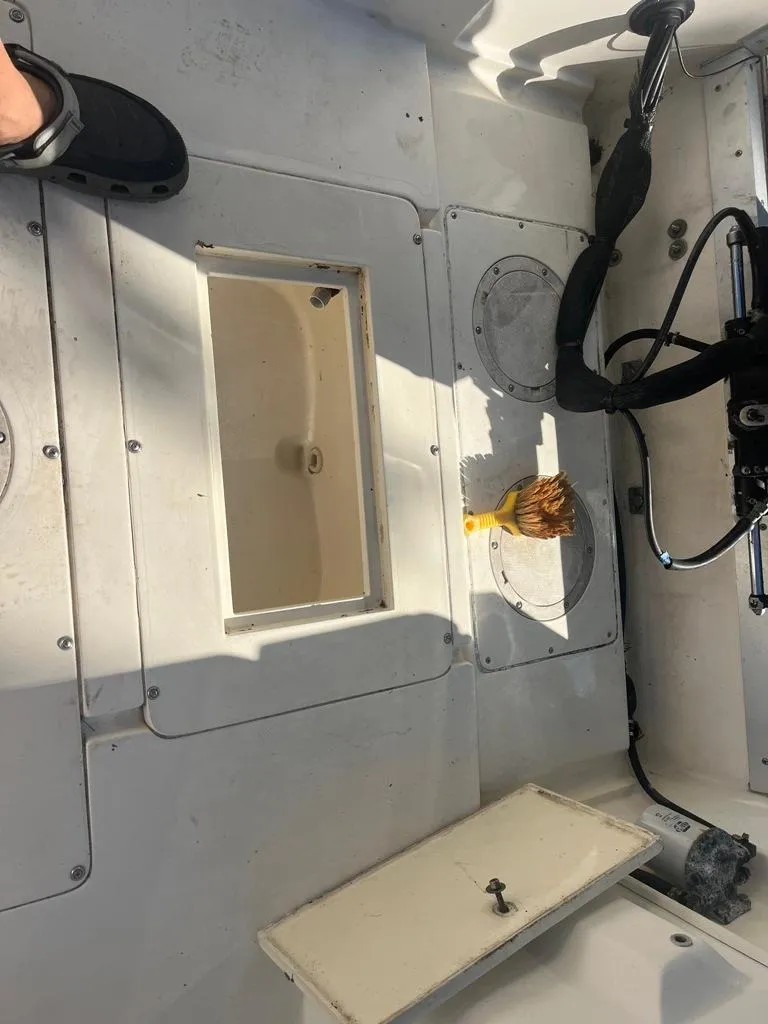 Slide: The Image of 1989 Mako 210 WA boat deck with open hatch and cleaning brush. - 31