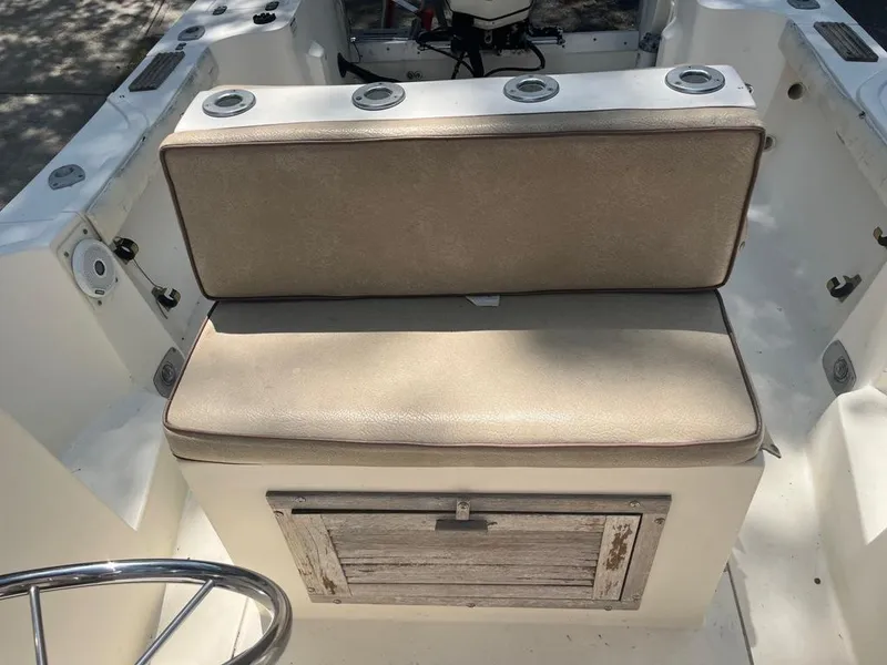 Slide: The Image of 1989 Mako 210 WA boat interior with beige cushioned seat and storage compartment. - 33