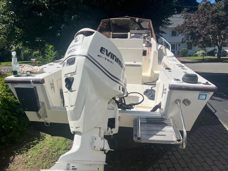 Slide: The Image of 1989 Mako 210 WA boat with Evinrude engine, parked on a driveway. - 6