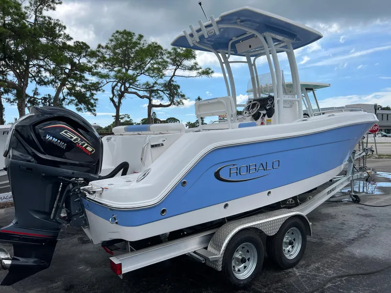 Slide: The Image of 2023 Robalo R222 Center Console boat on trailer with Yamaha engine, parked outdoors. - 2