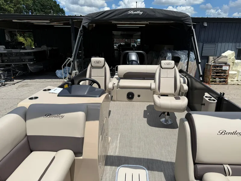Slide: The Image of 2026 Bentley Pontoons Legacy 243 Swingback interior with luxurious seating and helm, parked outdoors. - 5