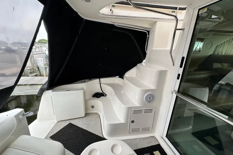 Slide: The Image of 2002 Sea Ray 400 Sedan Bridge interior with steps, seating, and black canopy. - 14