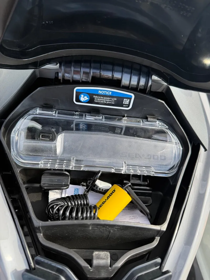 Slide: The Image of 2024 Sea-Doo Fishpro Trophy 170 storage compartment with accessories and safety notice. - 14